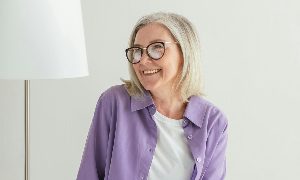 Middle-aged woman wearing a purple shirt smiling 