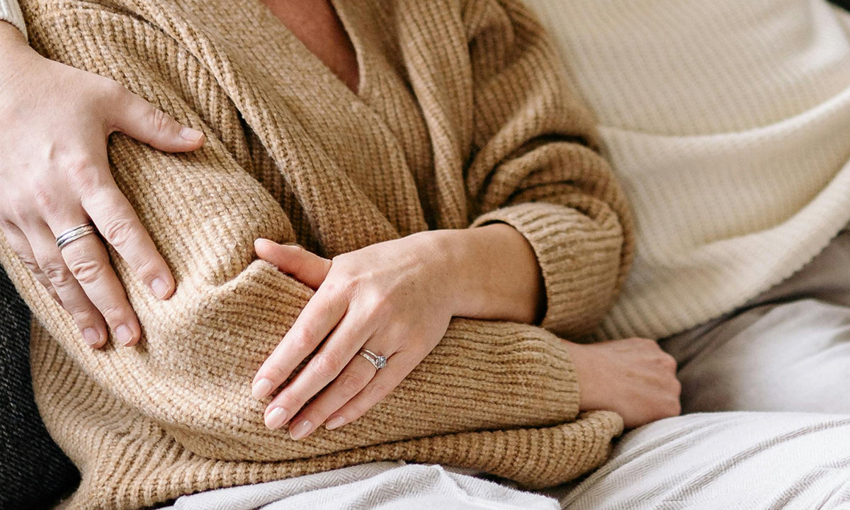 Older couple sitting side by side with his arm around her shoulders.