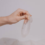 Hand holding a HydroSlix™ Vaginal Liner against a neutral background