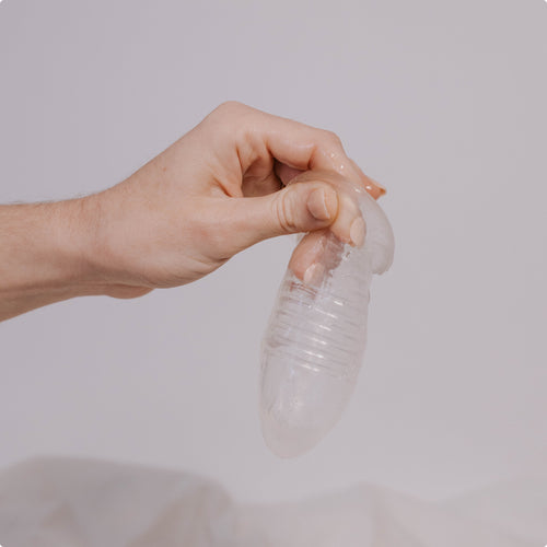 Hand holding a HydroSlix™ Vaginal Liner against a neutral background